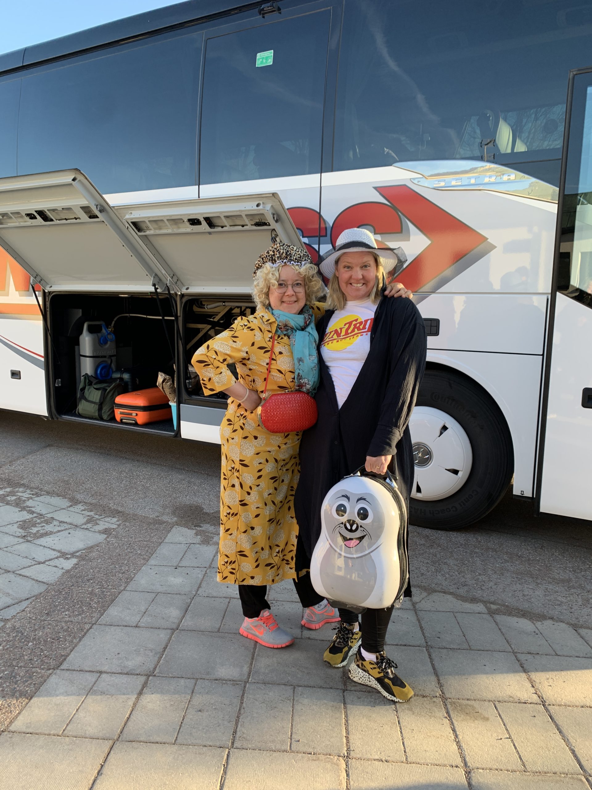 Två utklädda deltagare står framför bussen till Stockholm.