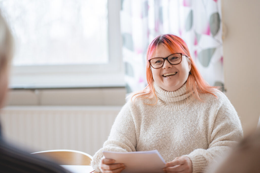 En glad person som redovisar ett arbete vänd mot kameran.